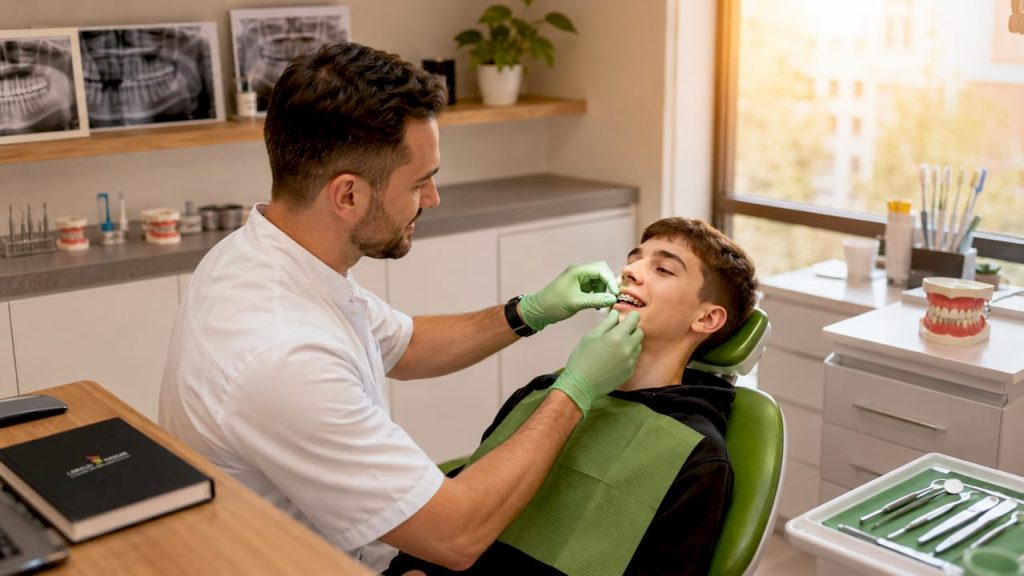 Medicul ortodont analizează modul în care sunt poziționați dinții unui adolescent, pentru a evalua dacă este nevoie de tratament.