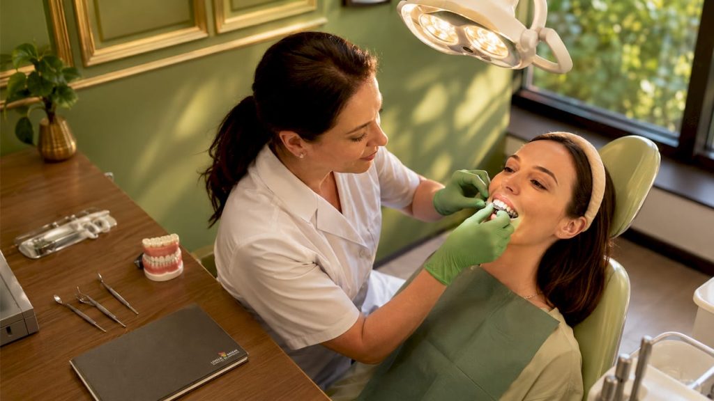 Medicul ortodont îi aplică pacientului gutiera Invisalign