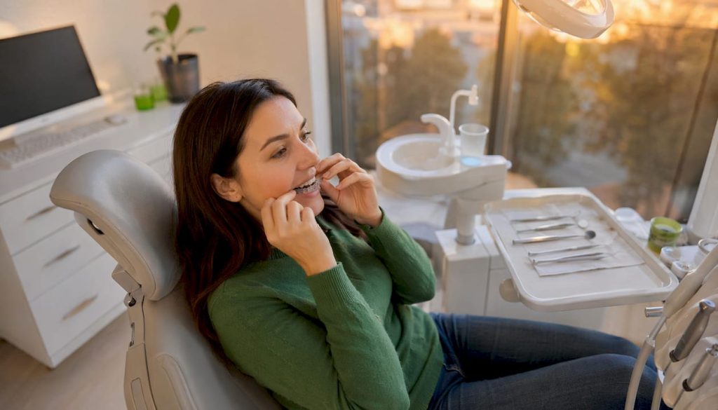 O femeie își montează gutiera Invisalign la stomatolog