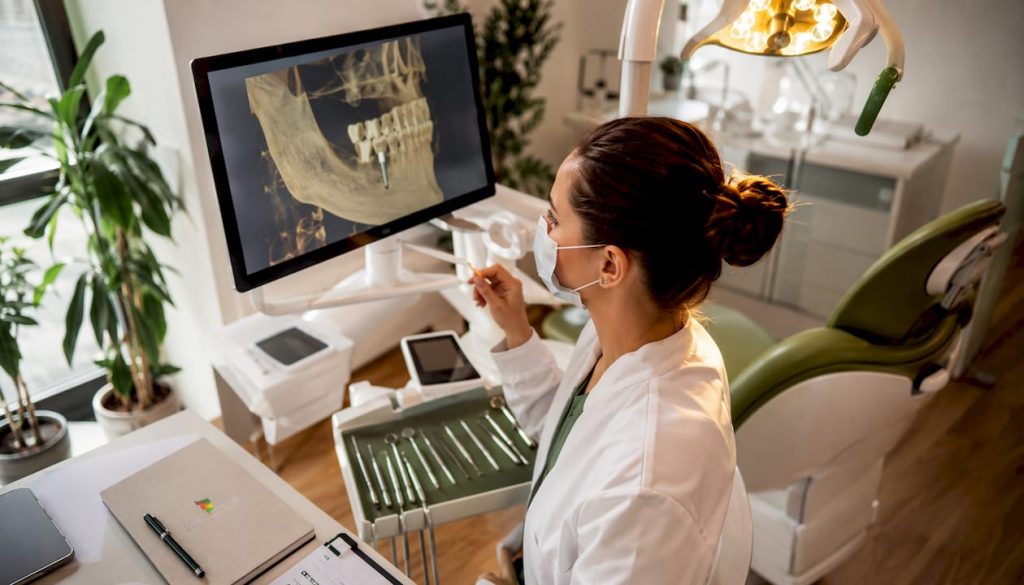 Un medic specialist în implantologie examinează imagini CBCT direct în cabinetul stomatologic, pentru a stabili cel mai bun plan de tratament.
