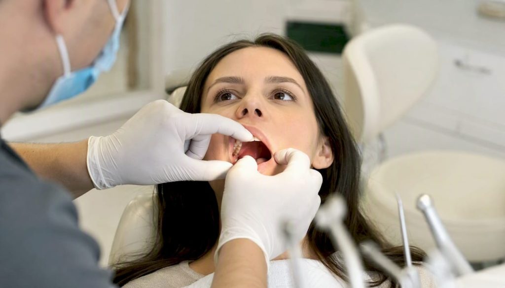 Medicul stomatolog verifică modul în care se vindecă gingiile după inserarea implantului dentar.