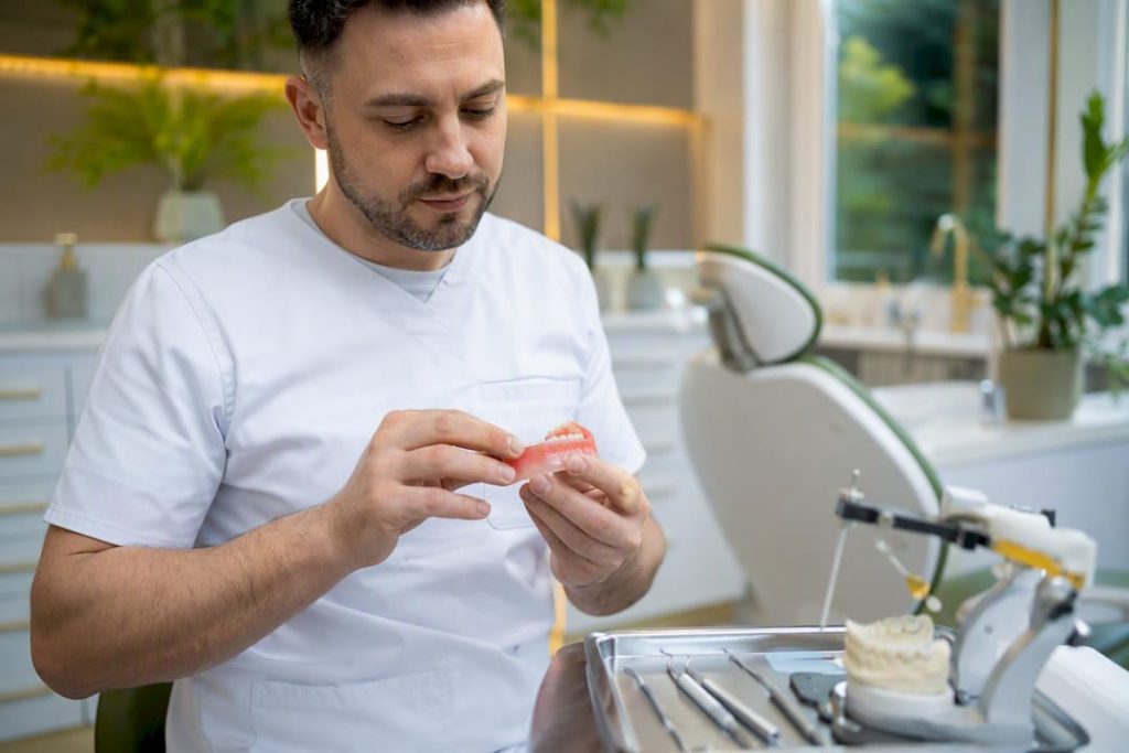Mâini de specialist ajustează o proteză dentară direct în cabinetul stomatologic.