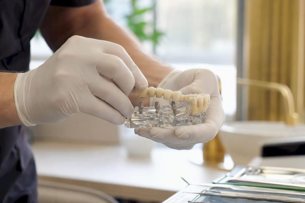 Medicul stomatolog montează o lucrare provizorie pe implant.