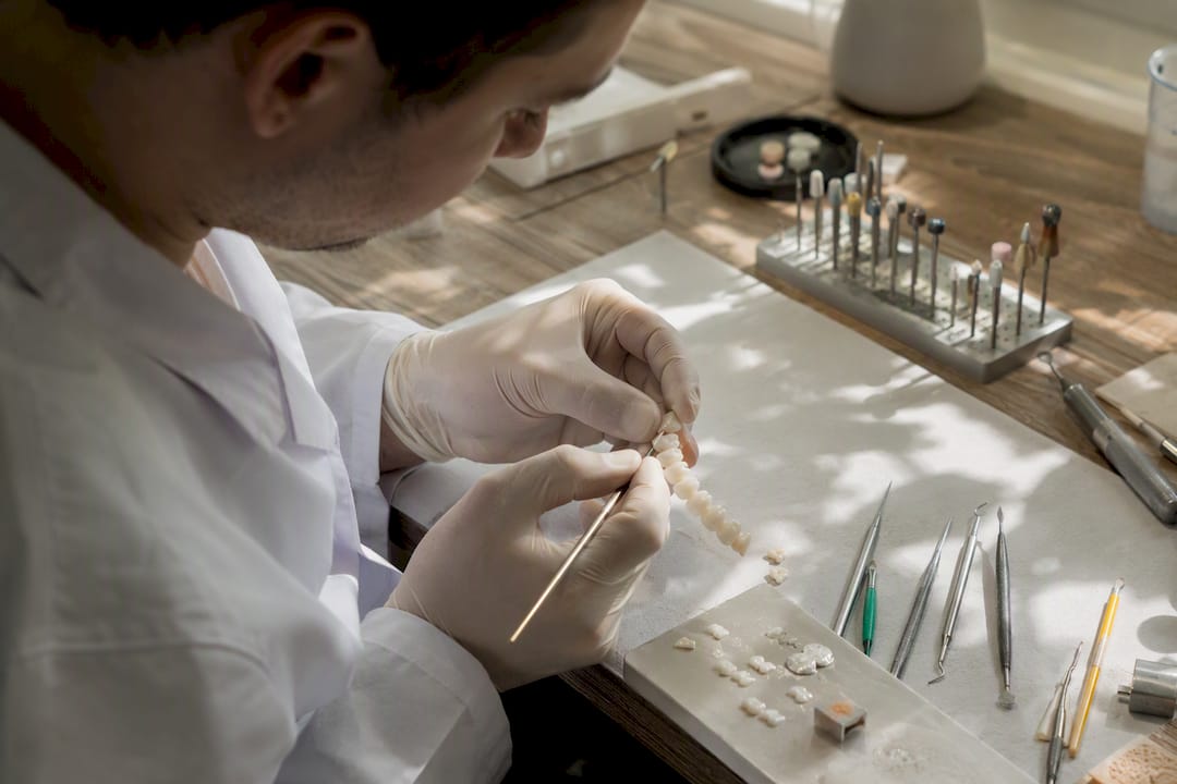 Mâinile tehnicianului modelează fațete dentare