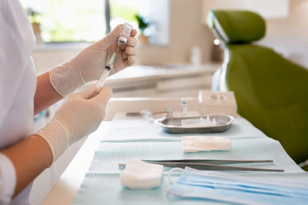 Mâna medicului care pregătește seringa cu acid hialuronic