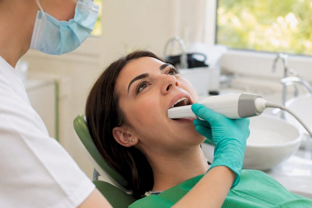 Dentist folosind un scanner intraoral în cavitatea bucală a pacientului